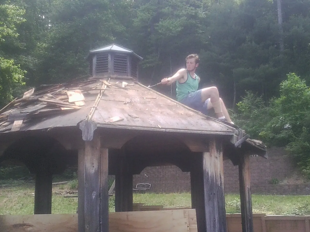 Tearing the old roof off a wooden gazebo before new shakes in Gerrardstown