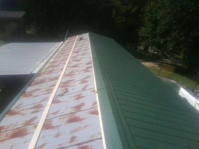 Old rusted panels beside newly installed green metal roofing — Wind Damage Roof Repair by Roofing Brothers in Gerrardstown