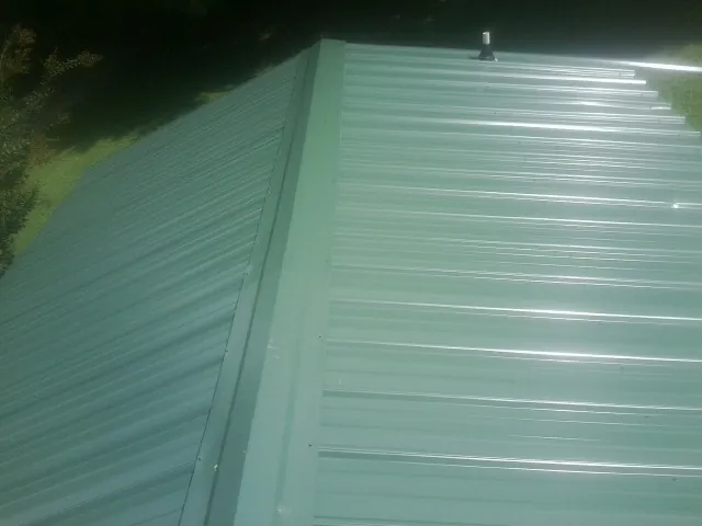 New green metal panels meeting at the ridge of a roof — Flat Roof Repair work by our crew in Gerrardstown