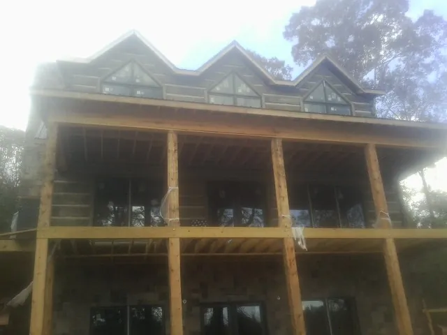 Dormers and porch framing on a large log home under construction — Roof Coating work by our crew in Gerrardstown
