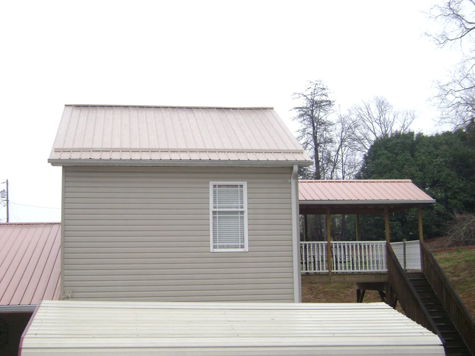 Tan metal roofs on a two story addition and attached porch, from a Roof Replacement job in Gerrardstown