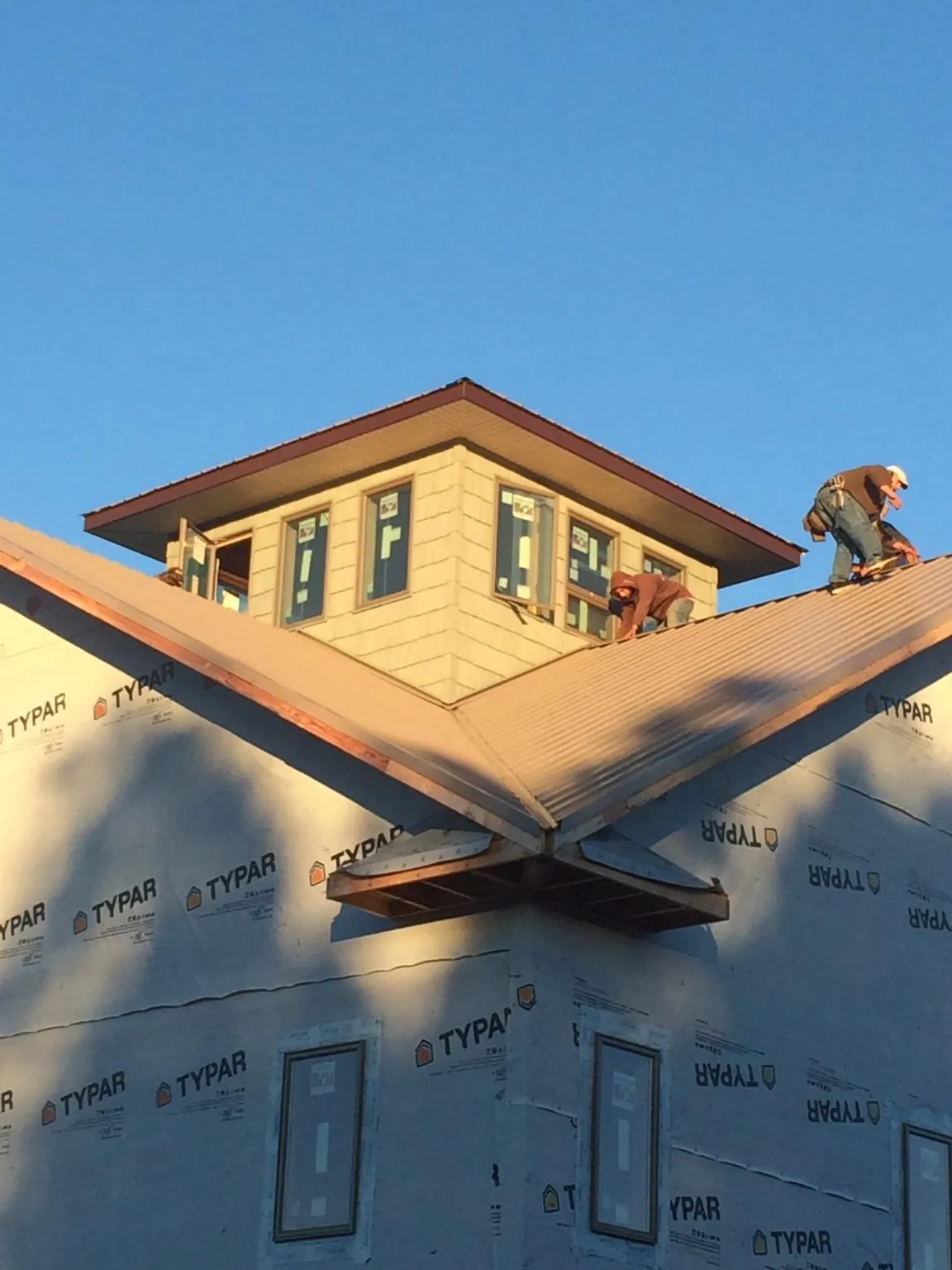 Roofers working around a rooftop cupola on a new metal roof at sunset — Roof Waterproofing in Gerrardstown by Roofing Brothers